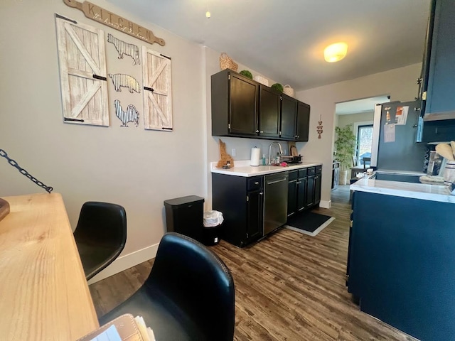 kitchen featuring a sink, baseboards, light countertops, appliances with stainless steel finishes, and dark wood-style floors