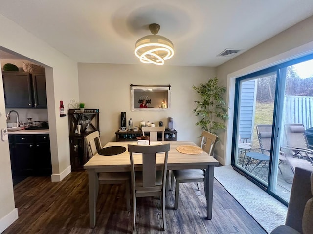 dining space with dark wood-type flooring, visible vents, and baseboards