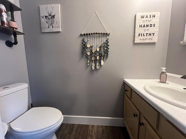 bathroom with toilet, baseboards, wood finished floors, and vanity