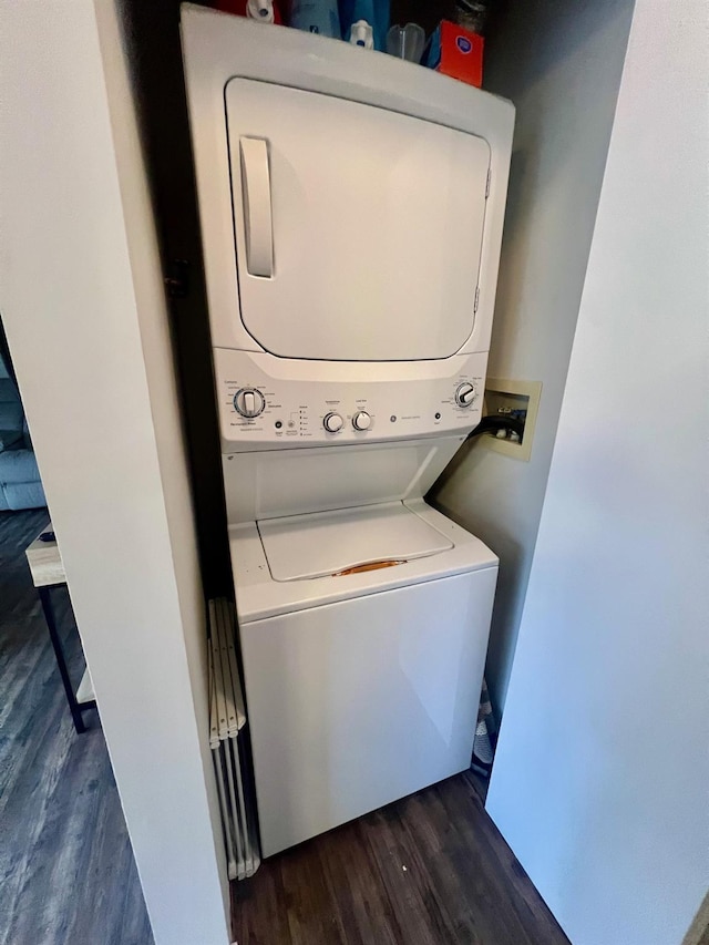 washroom featuring laundry area, dark wood-type flooring, and stacked washing maching and dryer