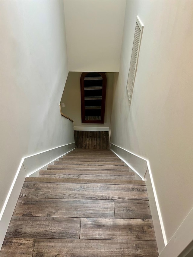 staircase with visible vents, baseboards, and wood finished floors