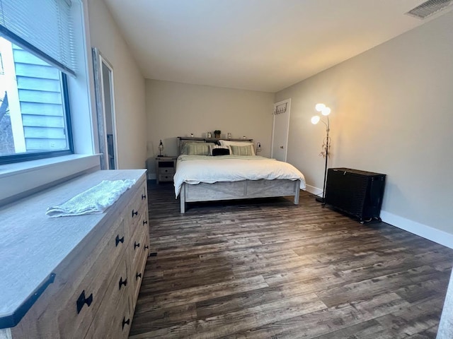 bedroom with dark wood-style flooring, visible vents, and baseboards