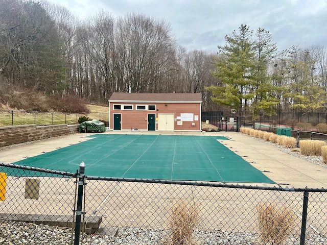 community pool with a patio area, fence, and an outdoor structure