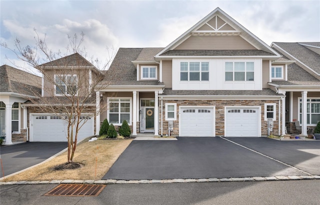 view of front of property with a garage, stone siding, driveway, and a shingled roof