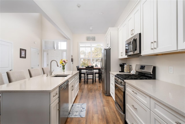 kitchen featuring a sink, light wood-style floors, light countertops, appliances with stainless steel finishes, and a center island with sink