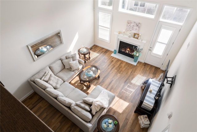 living area with a fireplace with flush hearth, baseboards, and wood finished floors