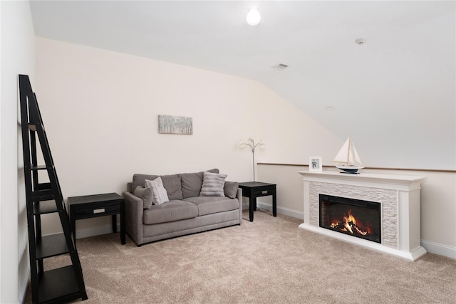 carpeted living area with visible vents, baseboards, vaulted ceiling, and a stone fireplace