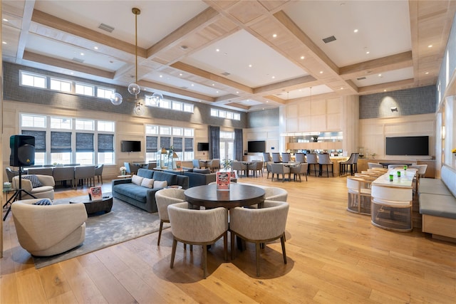 dining area with coffered ceiling, visible vents, light wood-style flooring, and a high ceiling