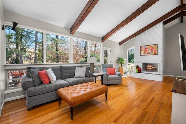 living room with lofted ceiling with beams, baseboards, a fireplace, and light wood finished floors