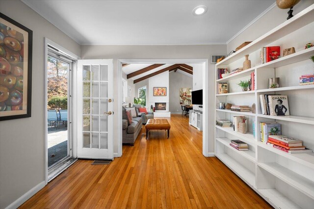 sitting room featuring light wood-type flooring, a large fireplace, baseboards, and vaulted ceiling with beams