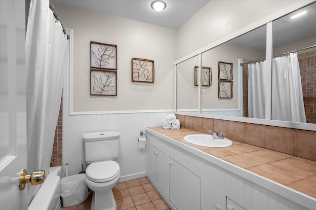 bathroom with vanity, tile patterned flooring, shower / bath combination with curtain, wainscoting, and toilet