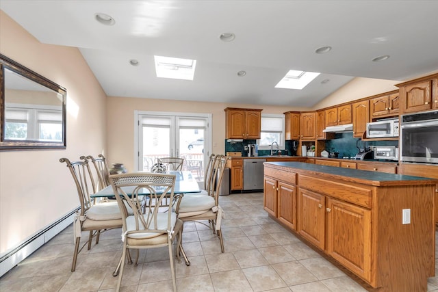 kitchen featuring brown cabinetry, dark countertops, lofted ceiling, stainless steel appliances, and under cabinet range hood