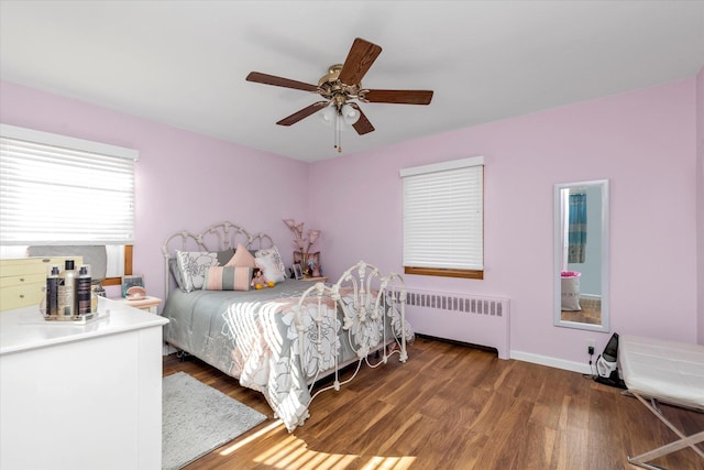 bedroom with dark wood-type flooring, radiator, ceiling fan, and baseboards