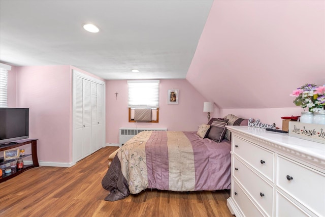 bedroom featuring baseboards, lofted ceiling, radiator heating unit, wood finished floors, and recessed lighting