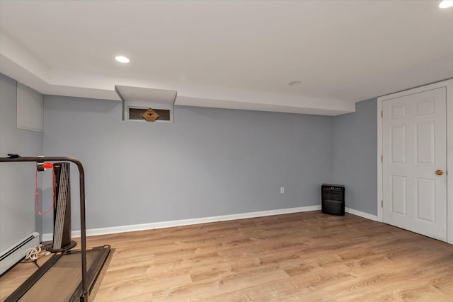 finished basement featuring light wood-type flooring, recessed lighting, a baseboard radiator, and baseboards