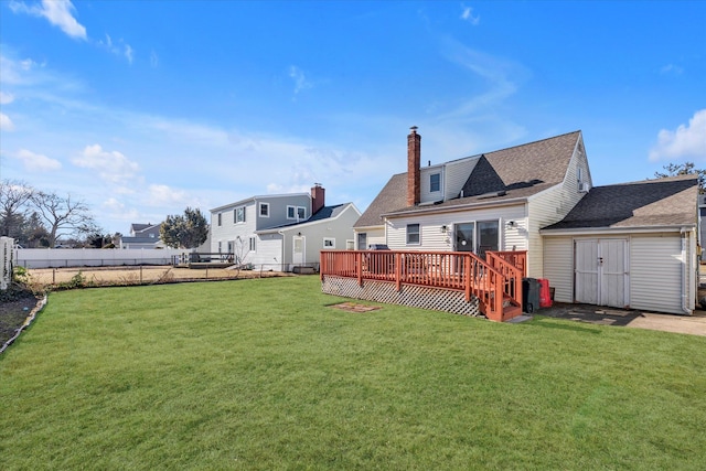 rear view of house with a fenced backyard, a yard, a deck, and a storage shed