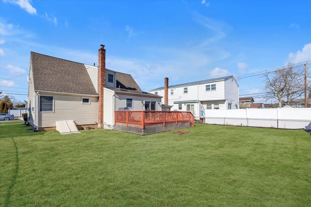 back of house with roof with shingles, a yard, a chimney, and a wooden deck