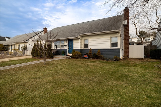 view of front of house with brick siding, fence, a chimney, and a front lawn