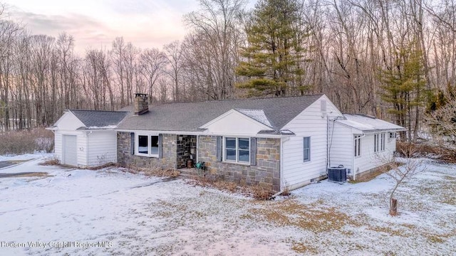 ranch-style house featuring a garage, stone siding, a chimney, and central AC