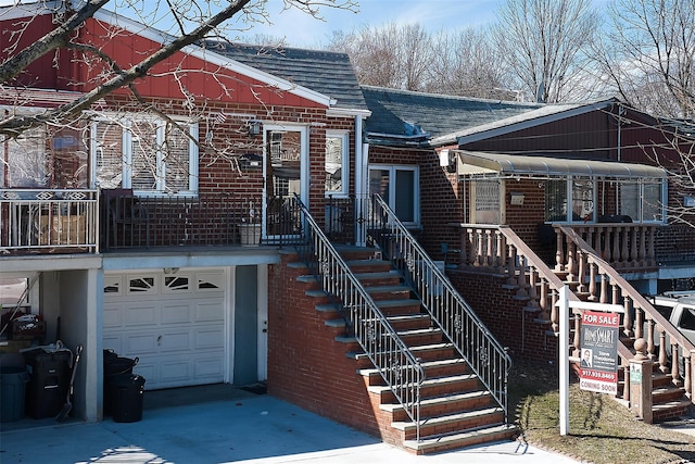 view of front of home featuring a garage, concrete driveway, brick siding, and roof with shingles