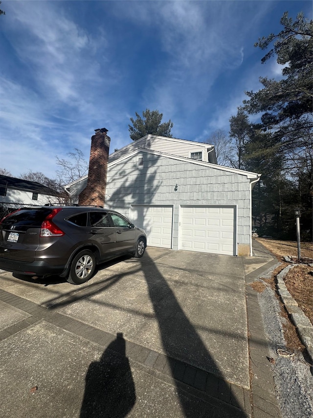 view of side of home featuring concrete driveway and an attached garage