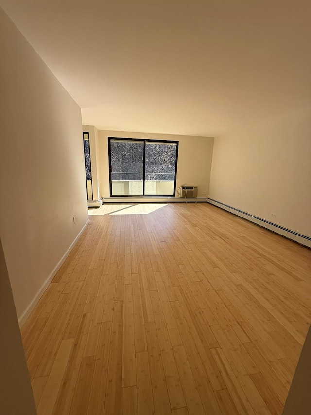 spare room with light wood-style floors, baseboards, and a baseboard radiator