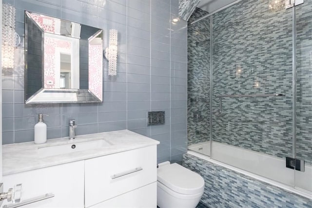 bathroom featuring toilet, tiled shower / bath combo, vanity, tile walls, and tasteful backsplash