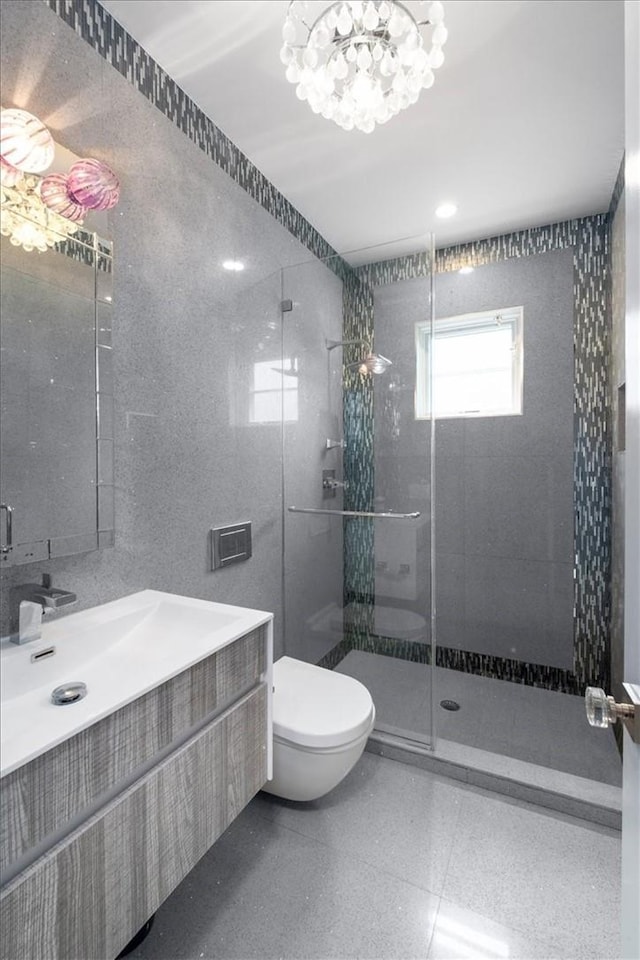 full bath featuring tiled shower, vanity, toilet, and tile walls