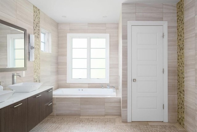 full bathroom featuring plenty of natural light, tile patterned flooring, a sink, and tile walls