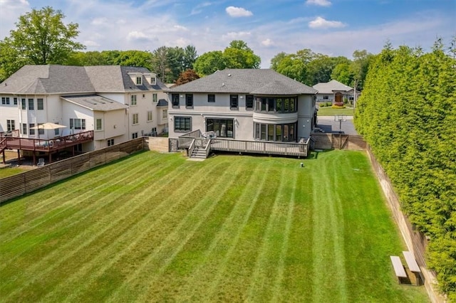 back of property featuring a deck, a lawn, a fenced backyard, and stucco siding