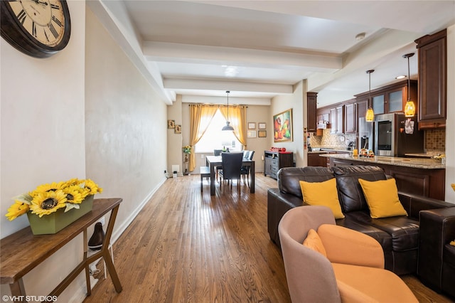 living room with baseboards, dark wood-type flooring, and beamed ceiling