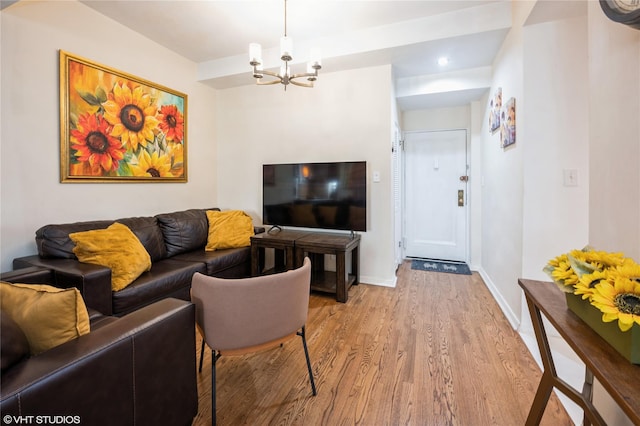 living room featuring baseboards, light wood finished floors, and an inviting chandelier