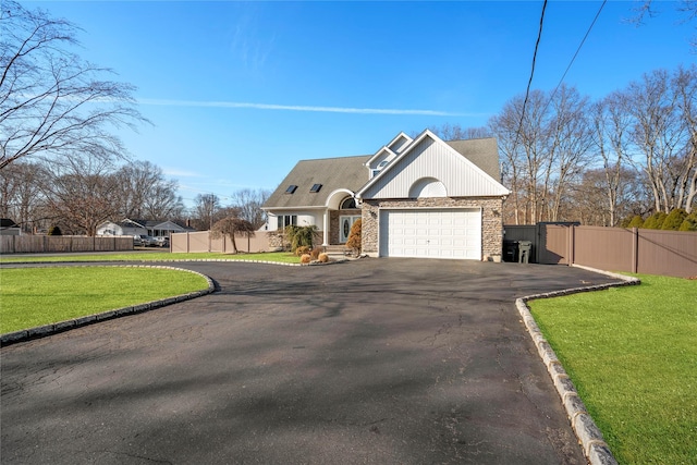 view of front facade featuring stone siding, a front lawn, fence, and driveway