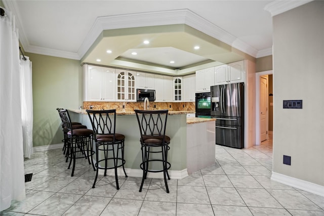 kitchen with stainless steel microwave, a breakfast bar, glass insert cabinets, a peninsula, and fridge with ice dispenser