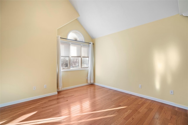 empty room with lofted ceiling, hardwood / wood-style flooring, and baseboards