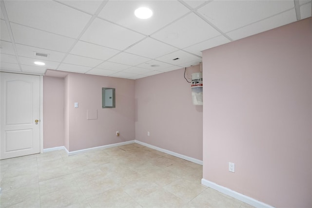 finished basement with a paneled ceiling, electric panel, and baseboards