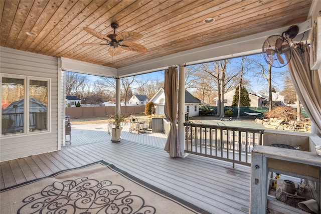 wooden terrace with an outdoor structure, fence, and a ceiling fan