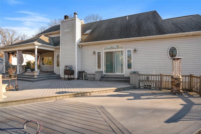 rear view of property with a shingled roof, a chimney, and a wooden deck