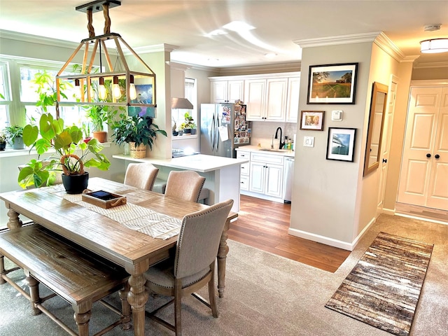 dining space featuring ornamental molding, light wood finished floors, and baseboards