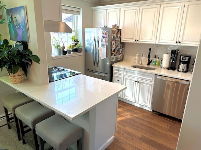 kitchen featuring dark wood-style floors, a breakfast bar, appliances with stainless steel finishes, white cabinets, and a sink