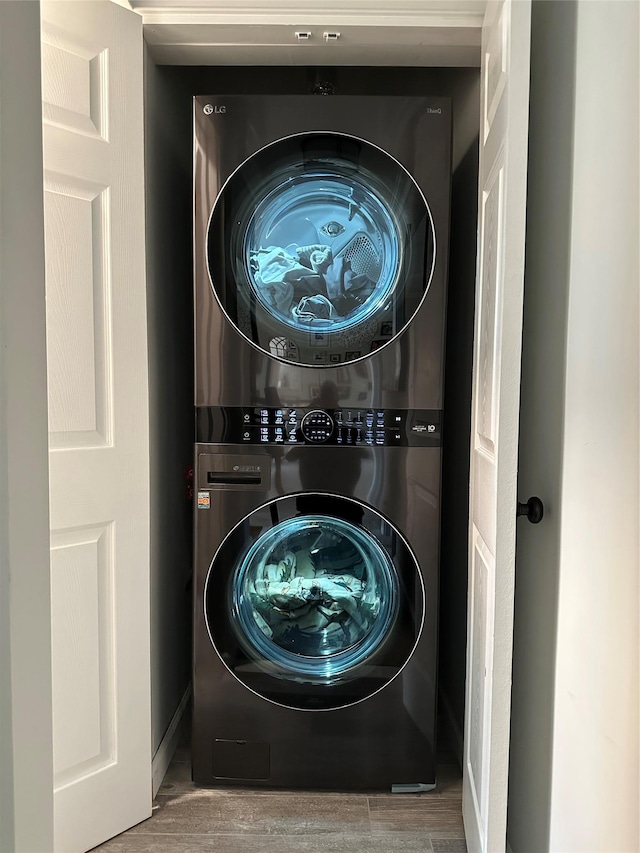 washroom featuring laundry area, wood finished floors, and stacked washer and clothes dryer