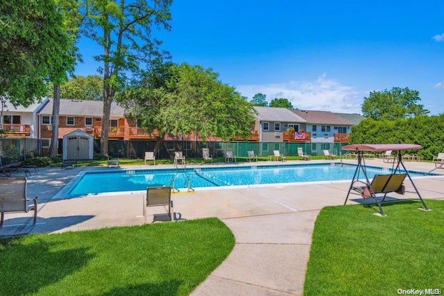 community pool featuring a storage unit, fence, an outdoor structure, and a yard