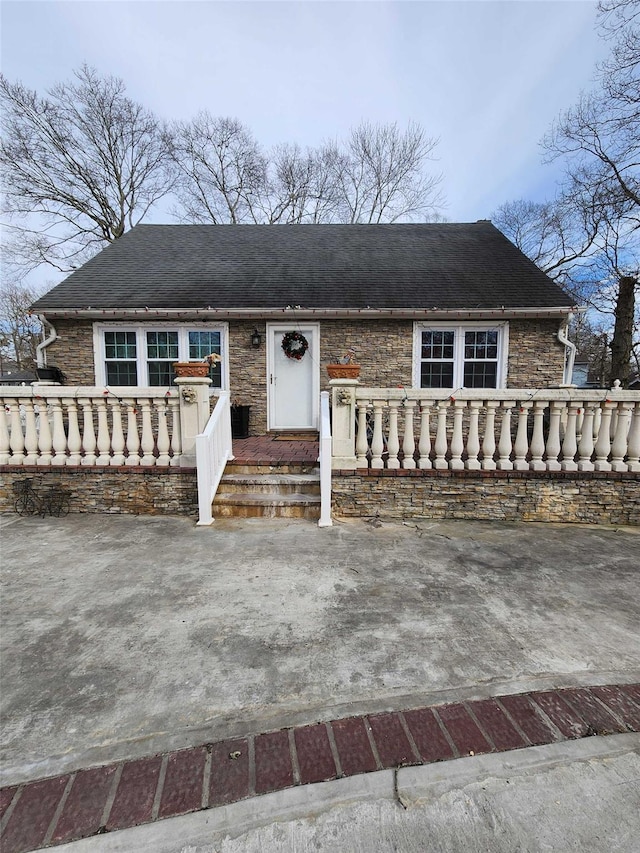 view of front of property with stone siding and roof with shingles