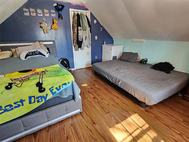 bedroom with lofted ceiling and wood finished floors