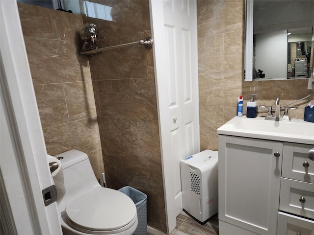 bathroom with toilet, tile walls, and vanity