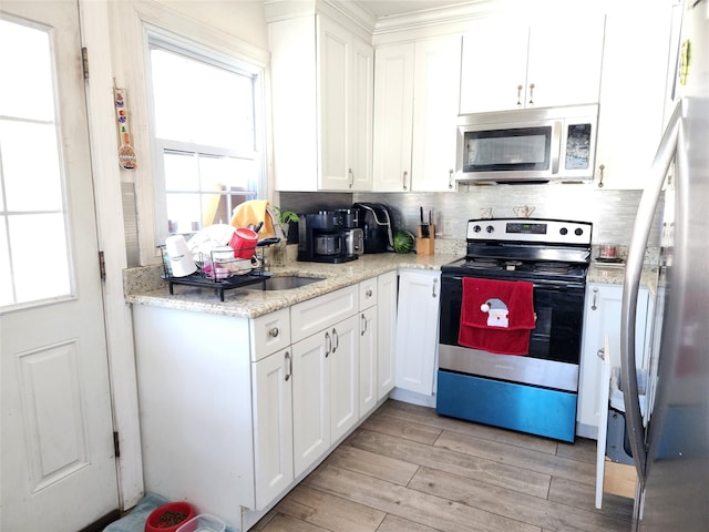 kitchen with appliances with stainless steel finishes, white cabinetry, and light wood finished floors