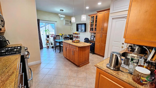 kitchen with stainless steel gas stove, glass insert cabinets, brown cabinets, light stone counters, and a center island