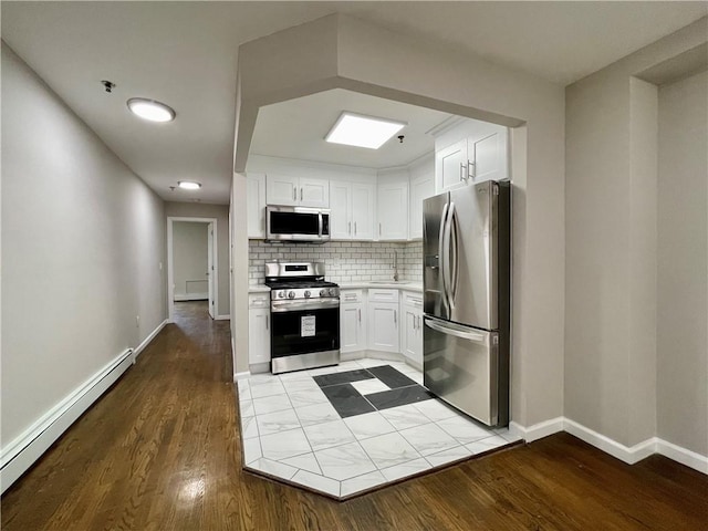 kitchen featuring appliances with stainless steel finishes, white cabinets, a baseboard heating unit, and decorative backsplash