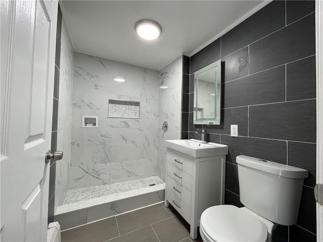 full bathroom with tile walls, a marble finish shower, vanity, and toilet