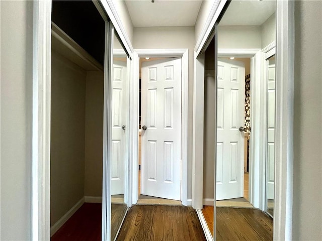 hallway with dark wood-style flooring and baseboards